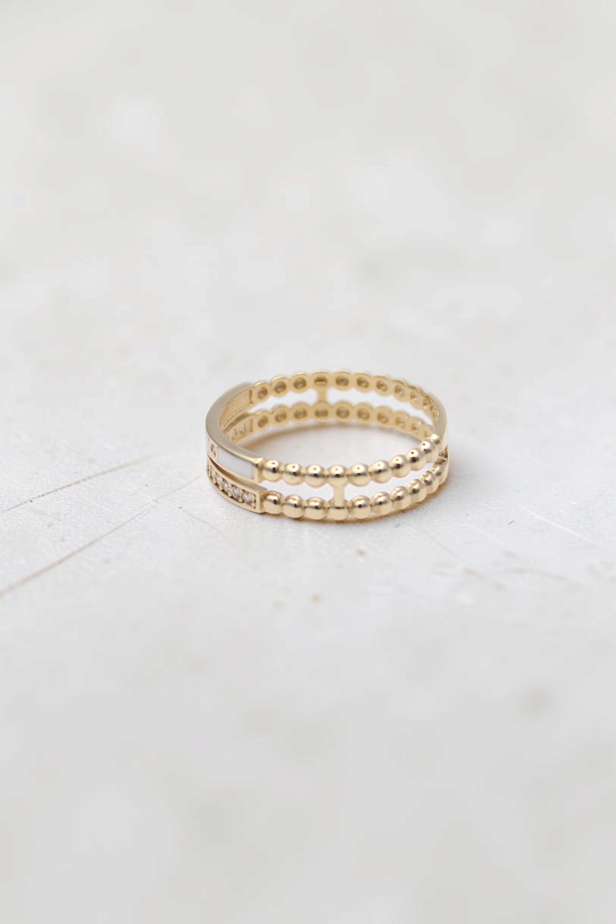 Zafrah 14k solid gold double beaded band ring featuring round clear stones and a smooth white inlay detail.