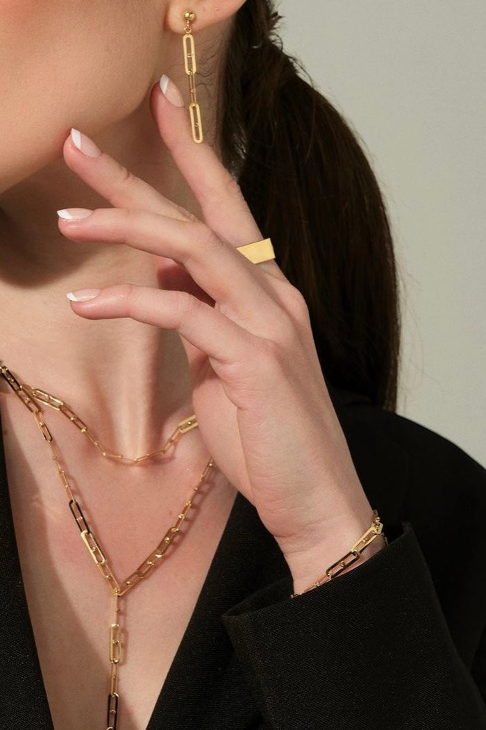 Zafrah 14k solid gold paperclip link bracelet worn on a woman's wrist, adjustable from 7 to 8 inches.