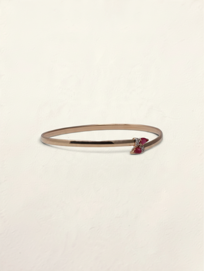 Zafrah 10k yellow gold bypass bangle featuring two pear-cut rubies and small round diamond accents.