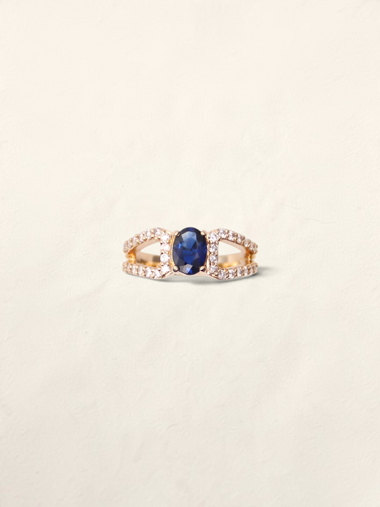 Zafrah 14k yellow gold ring featuring an oval dark blue topaz center stone surrounded by 32 round diamond accents.