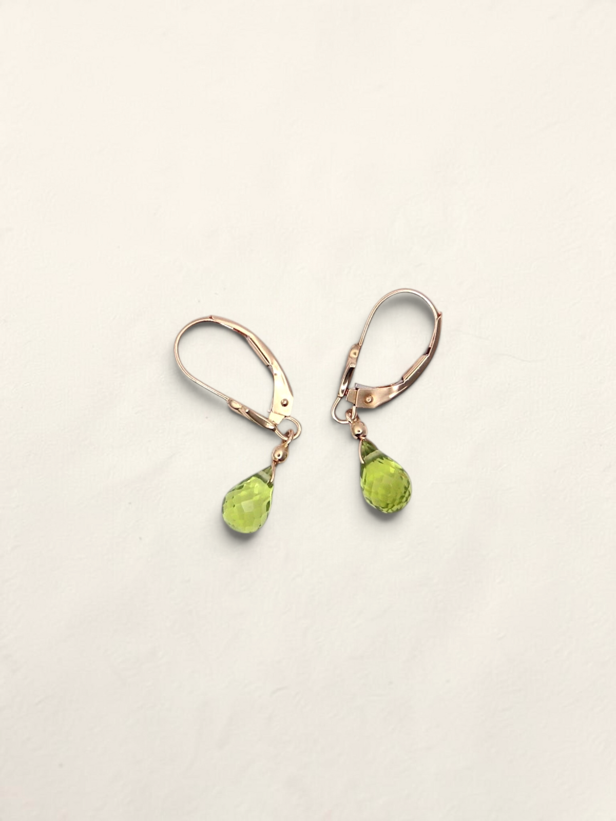 Zafrah 14K yellow gold huggie earrings featuring faceted pear-shaped green quartz drops on a light background