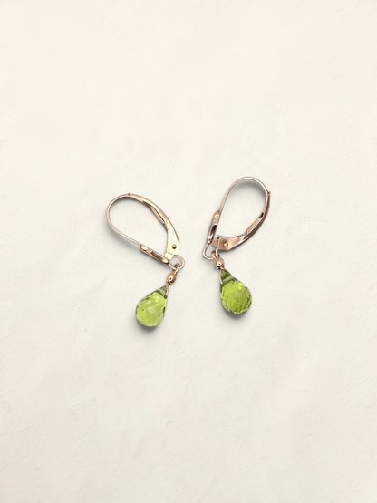 Zafrah 14K yellow gold huggie earrings featuring faceted pear-shaped green quartz drops on a light background