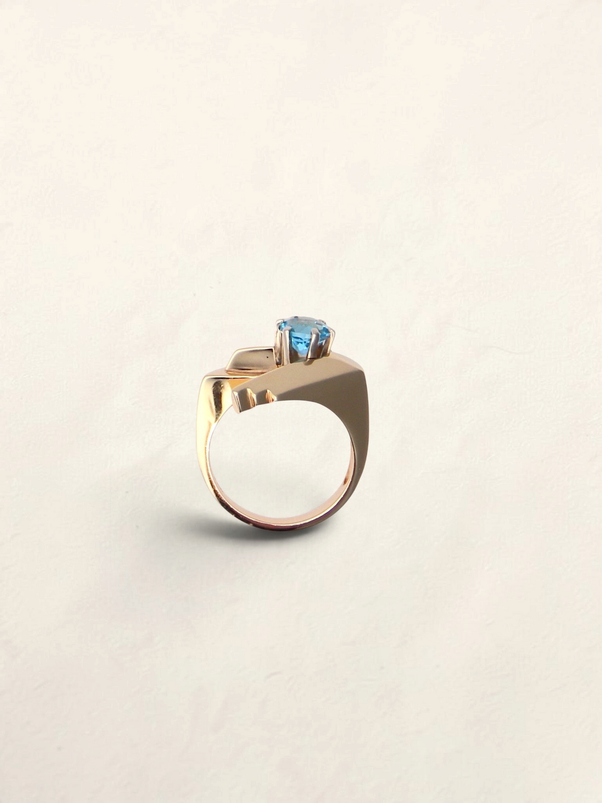 Zafrah 14K yellow gold abstract ring featuring a 1ct round blue topaz stone in a modern geometric setting.
