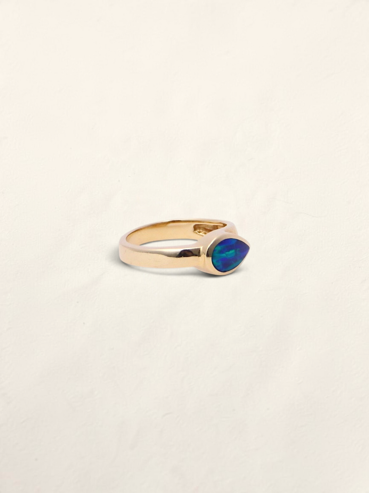Zafrah 14k yellow gold ring featuring a pear-shaped boulder opal inlay with vibrant blue and green flashes.