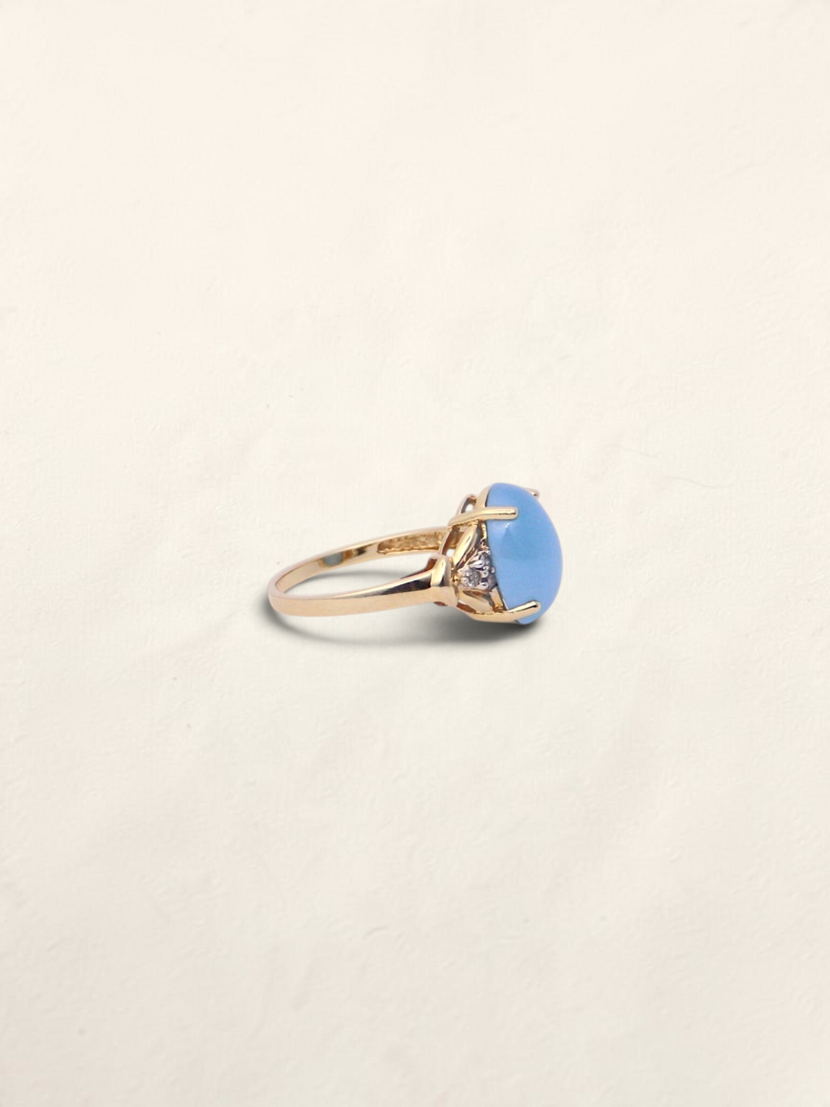Zafrah 14K yellow gold ring featuring an oval blue jadeite stone accented with round diamonds, side profile view.