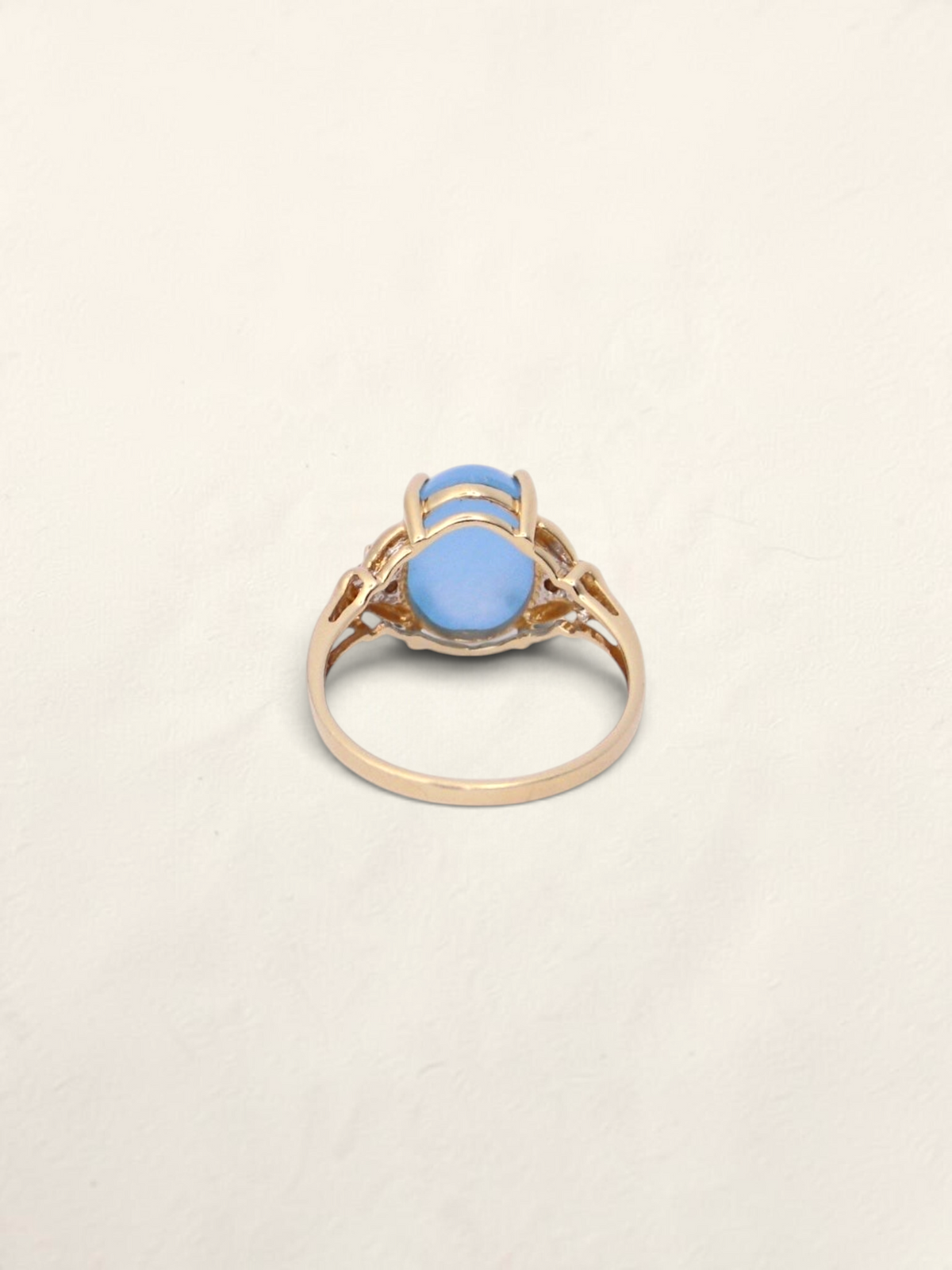Zafrah 14K yellow gold ring featuring an oval blue jadeite stone and diamond accents on a light background.