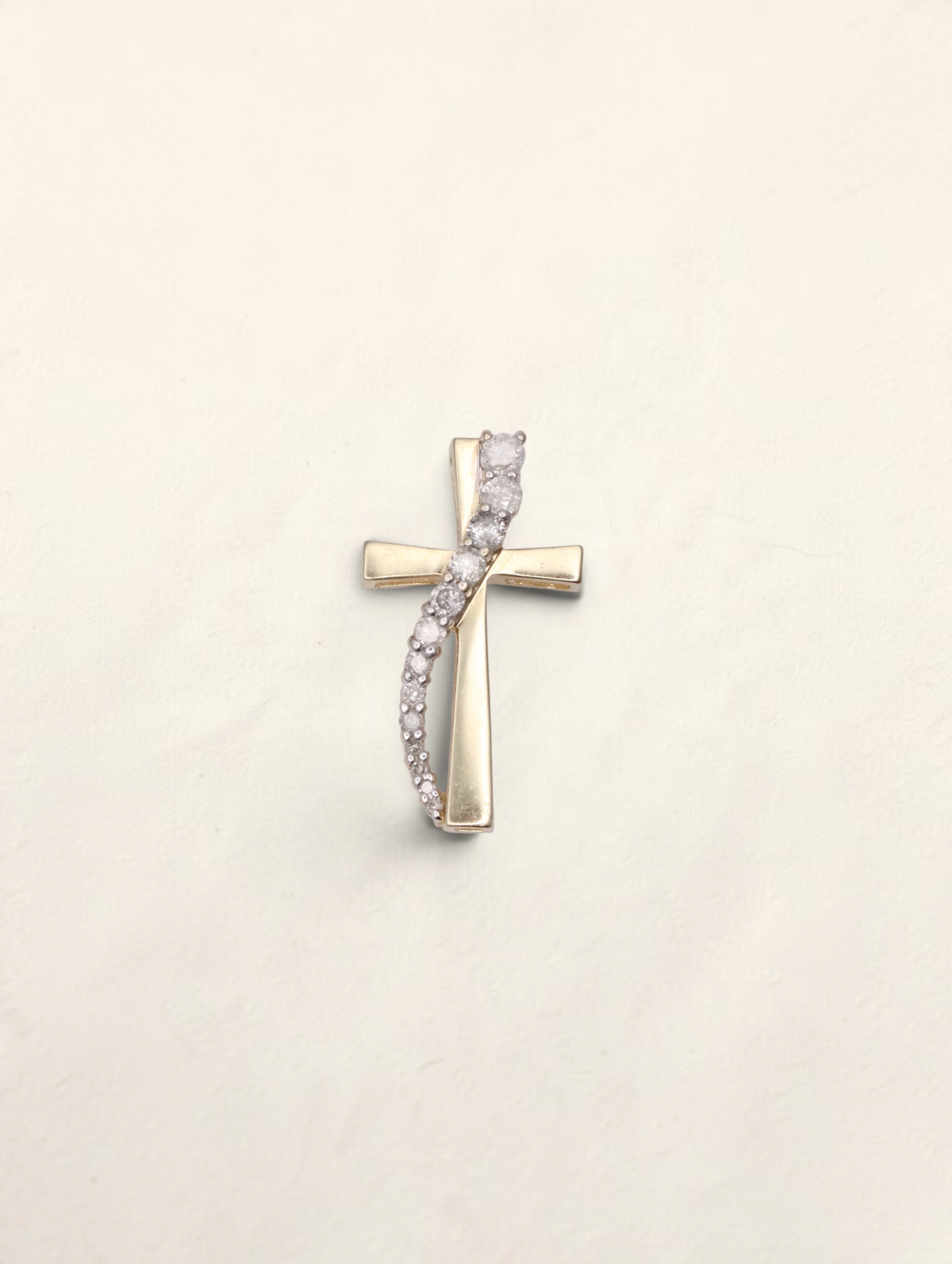 Zafrah 10k yellow gold cross pendant featuring a curved row of graduated round diamonds on a polished gold base.