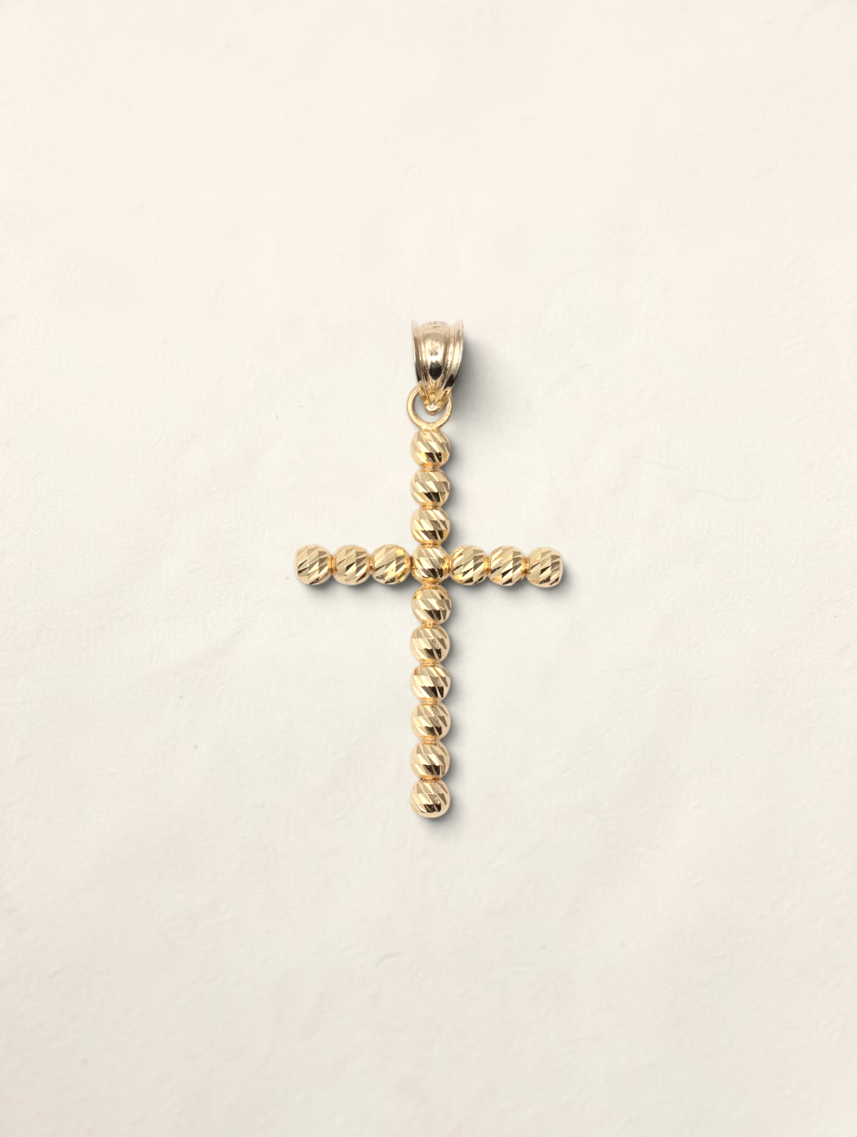 Zafrah 10k yellow gold cross pendant featuring a textured moon cut bead design on a white background