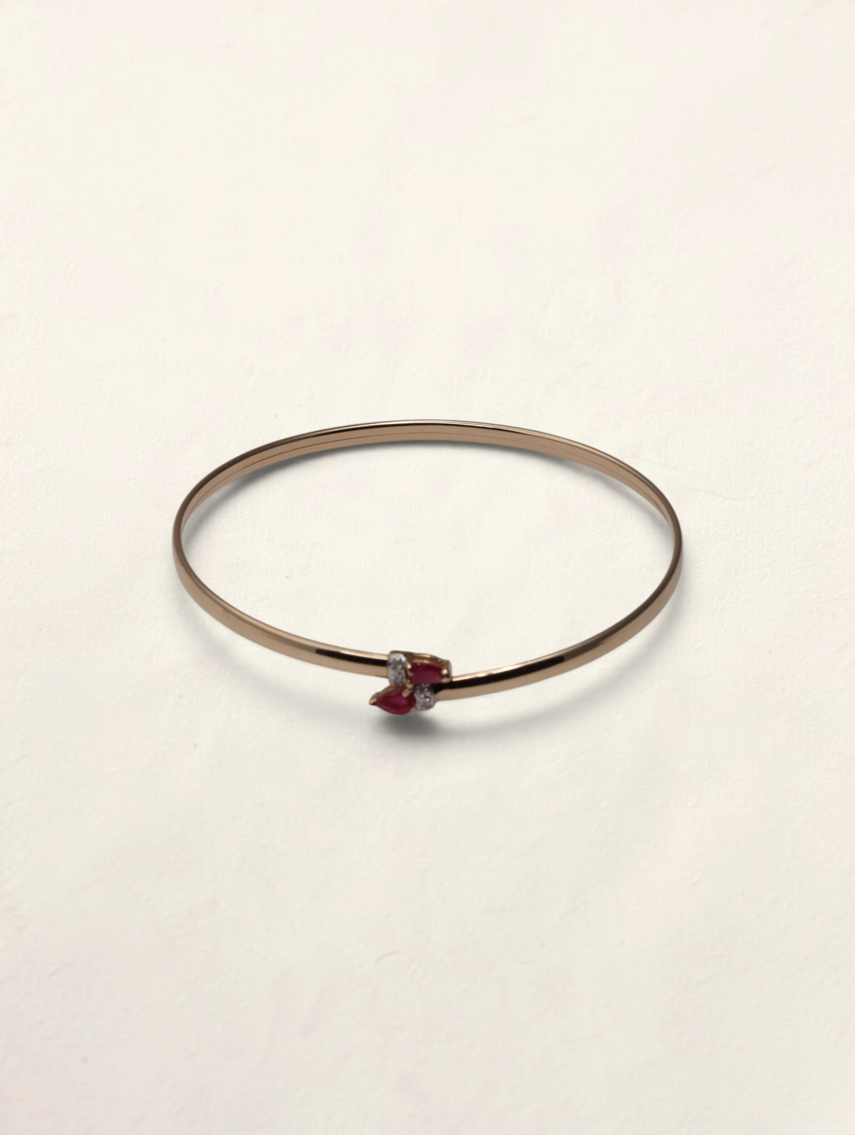 Zafrah 10k yellow gold bypass bangle featuring two pear-cut rubies and four small round diamonds