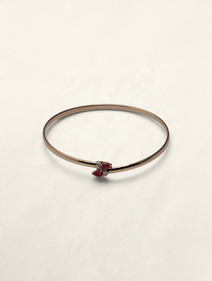 Zafrah 10k yellow gold bypass bangle featuring two pear-cut rubies and four small round diamonds