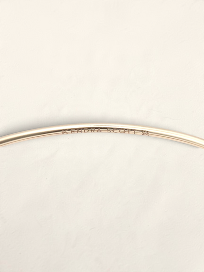 Zafrah 14K yellow gold Kendra Scott bangle showing the interior hallmark engraving